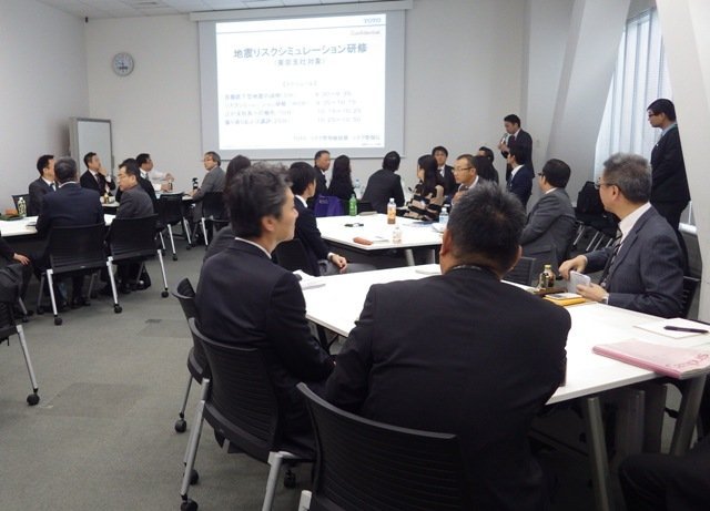 会議室にて、社員がスクリーンを見ながらリスクシミュレーションを行っている。