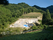 鉱山の採掘が完了した地域で植林が行われている写真。山肌がむき出しになった部分と、植林された緑のエリアが混在している。