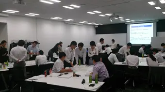 Group work in a conference room. Participants are divided into several groups and sit around a table to discuss.